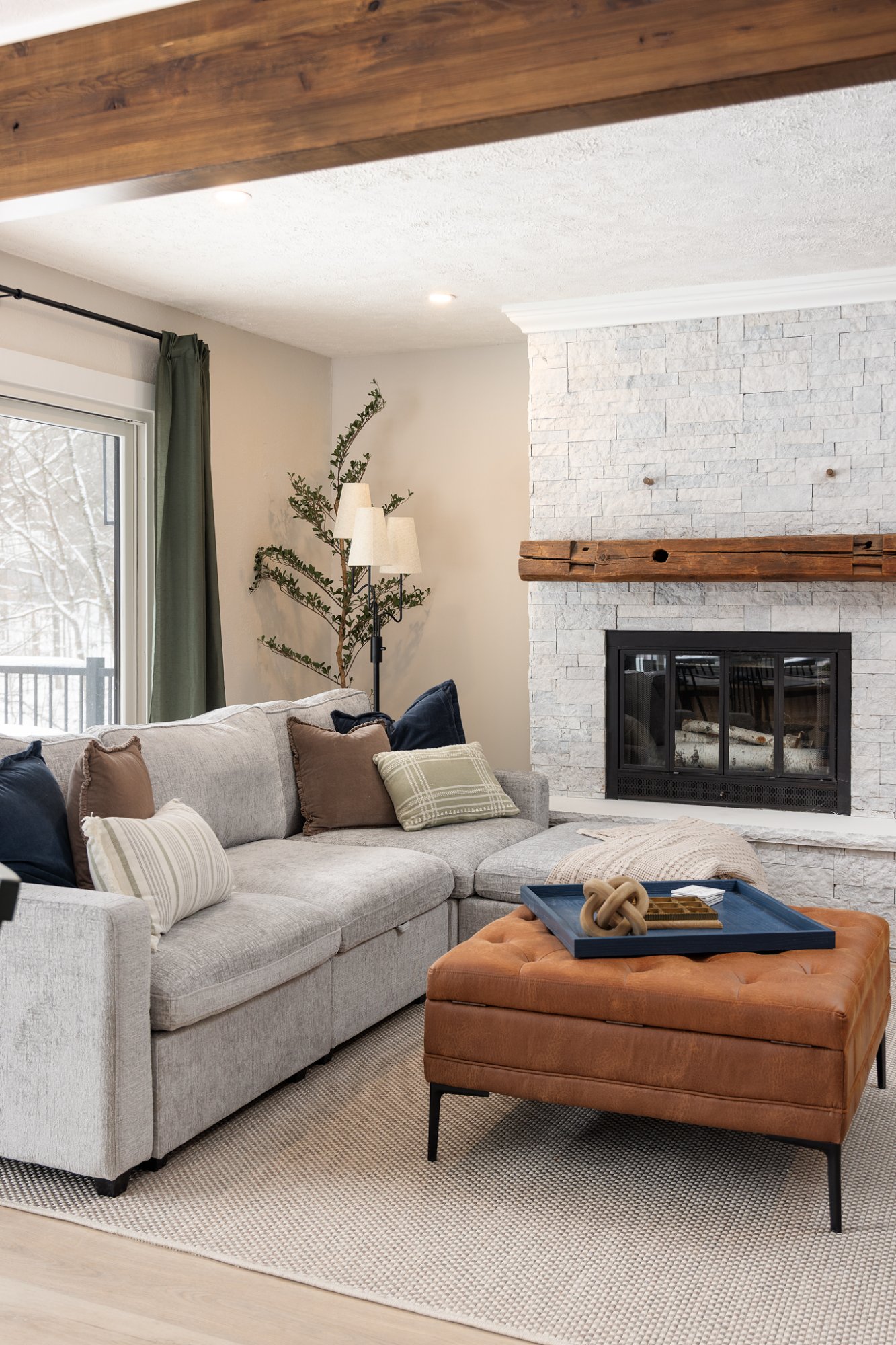 Sectional sofa with stone fireplace and leather ottoman